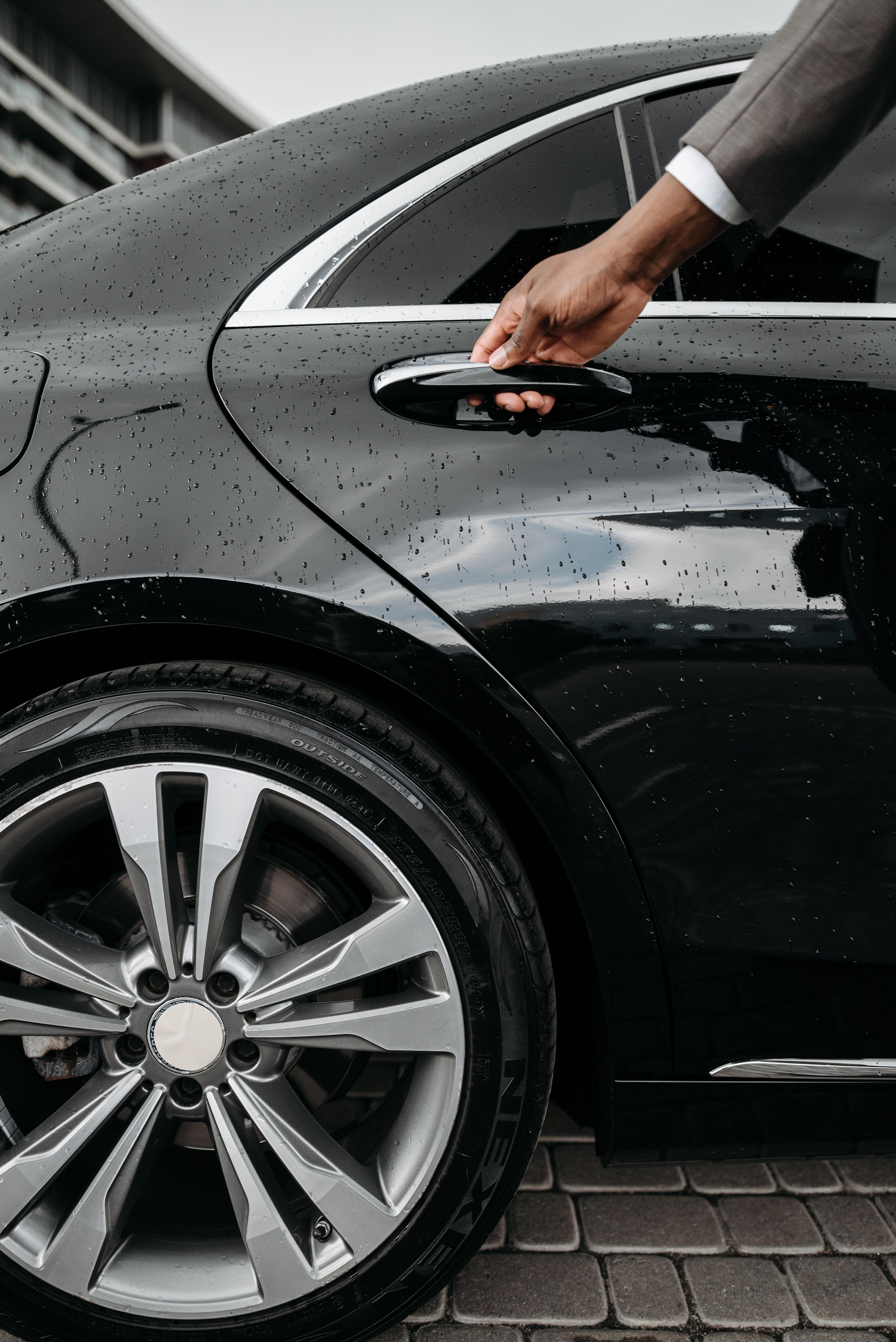 Chauffeur opent het portier van een gepantserde luxewagen voor beveiligd vervoer